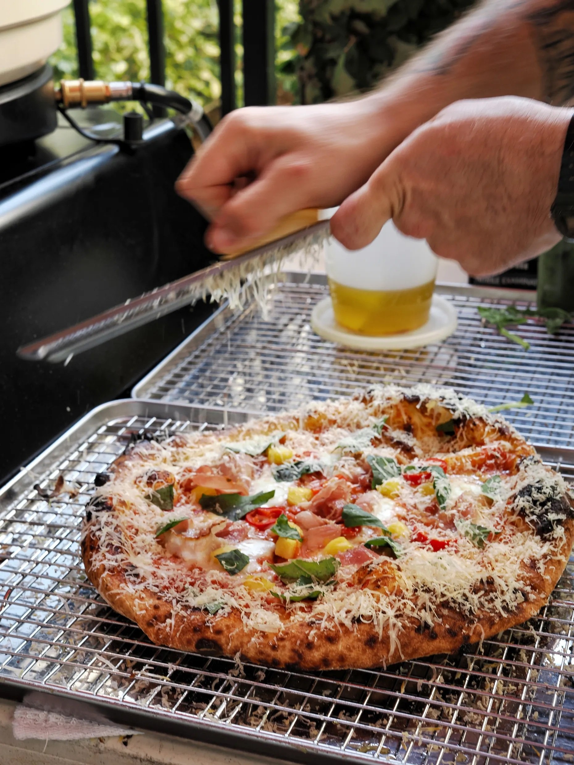Aged gouda being grated over a Burnt Mouth Pizza pie at an Orlando pop-up